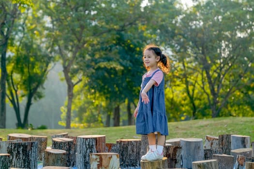 Little Asian girl stand on timber and look fun with playing in park or garden.