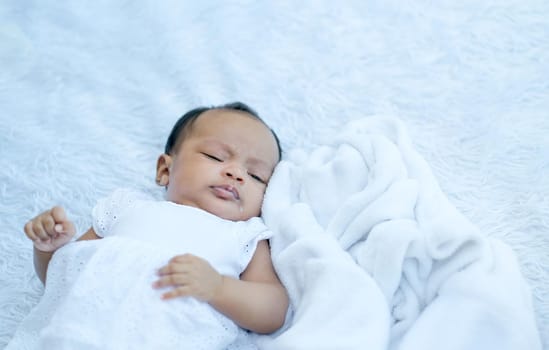 Little baby with white cloth lie and sleep after eat milk on white carpet in the garden with morning light.