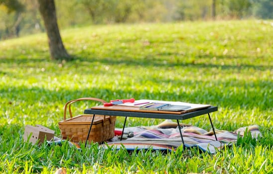 The table over carpet with colored pencils and toys are set in the green garden with the concept happy holiday with child.