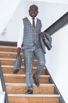 Successful Young Businessman. African American Guy Descends Stairs To Work In Morning. Concept Of Luxurious, Rich Life. High quality photo.