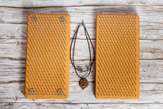 Om Symbol Necklace. Brown Sadhu wooden boards with nails for yoga and spiritual practices on the grey background. The concept of meditation, standing on nails, therapy.