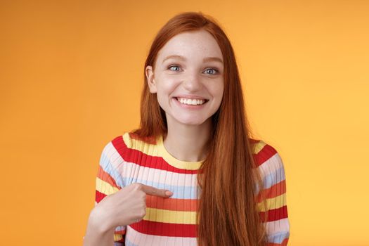 Happy excited grinning redhead girl chosen smiling gratitude delighted gladly pointing herself look surprise thankful camera got job, receive scholarship standing orange background. Copy space
