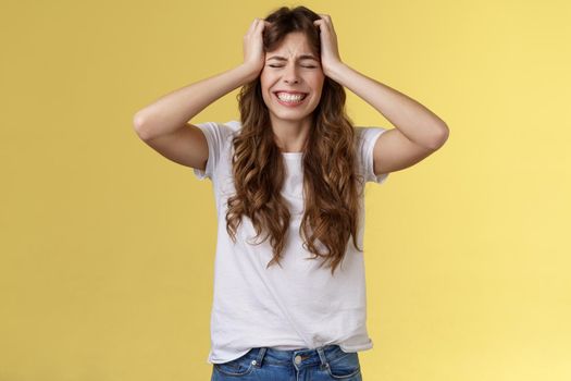 Girl feeling huge pain suffer heartbreaking break-up grab head panicking close eyes clench teeth anxiously troubled feel distress terrible situation stand yellow background hopeless grieving. Lifestyle.