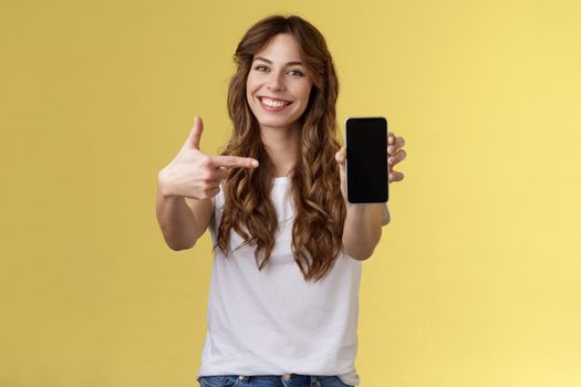 Upbeat confident good-looking female showing photo smartphone display hold mobile phone extended arm camera pointing index finger cellphone screen smiling delighted promote app internet application. Lifestyle.