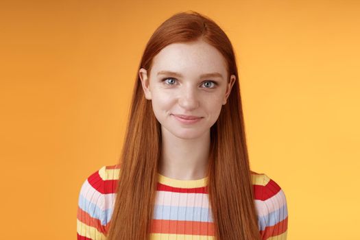 Attractive self-assured redhead girl encouraging herself look mirror confident prepare interview speech standing orange background smirking intrigued listening talking casually.