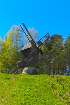 An old wooden mill against the backdrop of a green forest