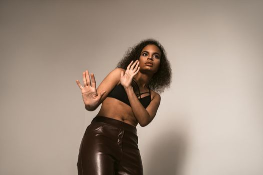 Scared with blocking hands young girl stands pinched, wearing leather pants and black top. Women violence and abused concept. trafficking Concept.