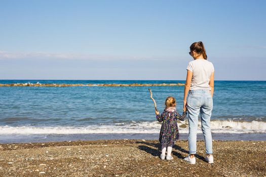 Back view of happy mother and little daughter at caribbean beach