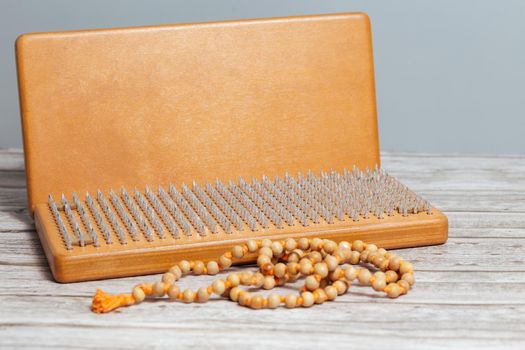 Tibetan Buddhist rosary, called mala or japamala. Brown Sadhu wooden boards with nails for yoga and spiritual practices on the grey background. The concept of meditation, standing on nails, therapy.