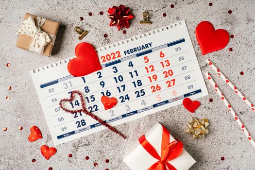 Flat lay of Valentines day calendar composition. Top view Gifts, paper, hearts confetti, ribbon on grey table background. 14th February love concept.