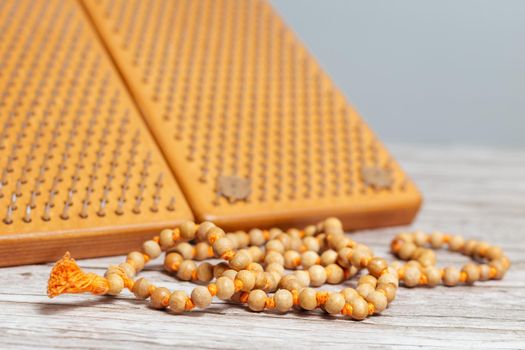 Tibetan Buddhist rosary, called mala or japamala. Brown Sadhu wooden boards with nails for yoga and spiritual practices on the grey background. The concept of meditation, standing on nails, therapy.