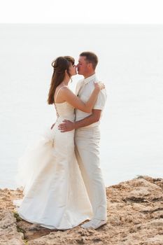Wedding, Beautiful Romantic Bride and Groom Kissing and Embracing Outdoors.