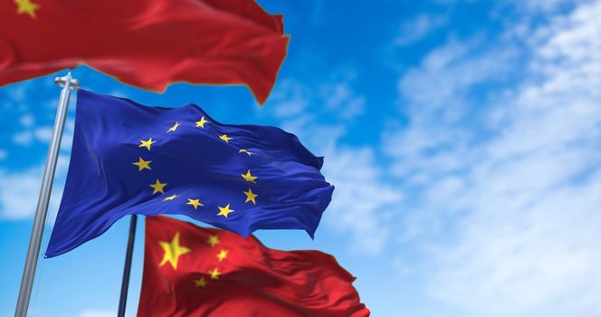 The flag of the European Union waving between two national flags of China. International relations and diplomacy.