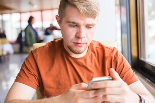 leisure, technology, communication and people concept - close up of man with smartphone texting message in city cafe.