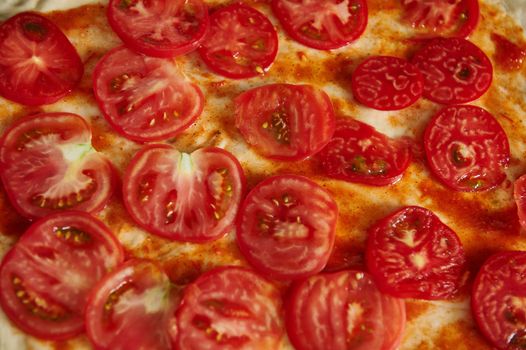 Close-up of tomatoes slices on pizza dough. Flat lay, top view, pattern. High angle view