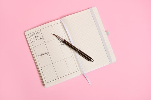 Flat lay of Planner templates and schedule of the day according to the hours marked in diary and with an ink pen lying on an open notebook. Business book diary, office organizer plans. Space for text