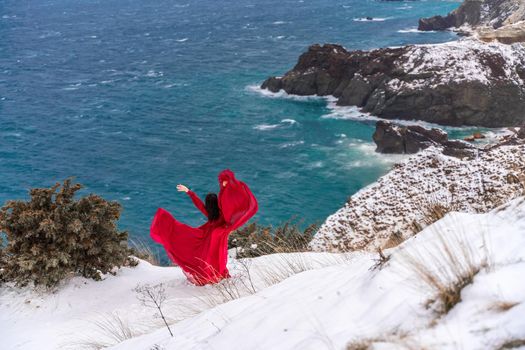 woman in a red dress high in the snowy mountains by the emerald lake.