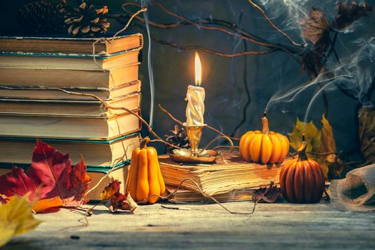 Old antique books with pumpkin shape candles on the wooden table. Halloween and fall season still life