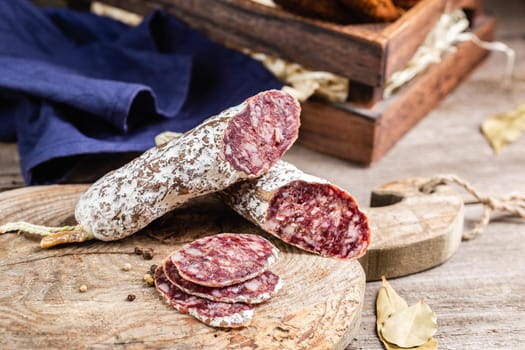 Smoked sliced salami on a old wooden table. Sausages with edible mold