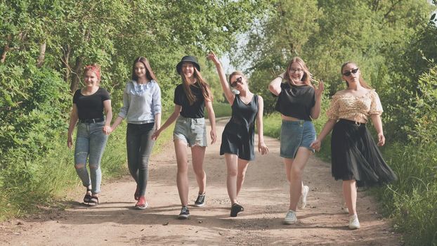 Schoolgirl friends are walking outside the city along a forest road