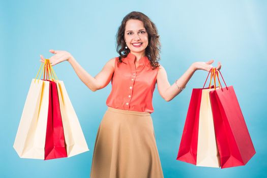 Young woman with shopping bags over blue background.