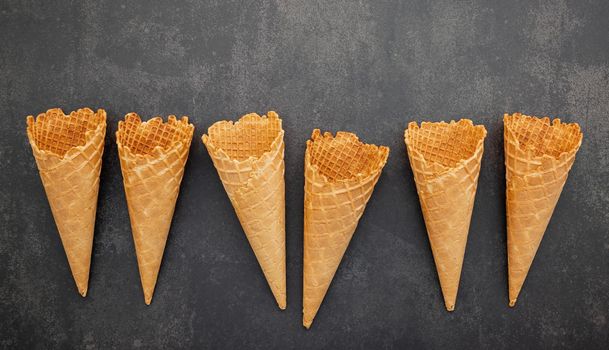 Flat lay ice cream cones collection on dark stone background . Blank crispy ice cream cone with copy space for sweets menu design.