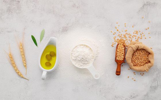 The ingredients for homemade pizza dough with wheat ears ,wheat flour and olive oil set up on white concrete background. top view and copy space.