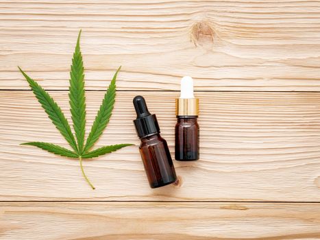 Glass bottle of cannabis oil and hemp leaves set up  on wooden background.