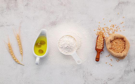 The ingredients for homemade pizza dough with wheat ears ,wheat flour and olive oil set up on white concrete background. top view and copy space.