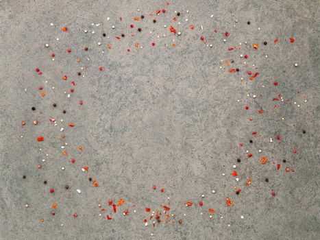 Top view of dark concrete background with peppercorn and chilli flakes.