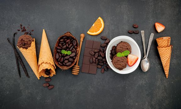 Chocolate ice cream flavours in bowl with dark chocolate and cacao nibs setup on dark stone background .