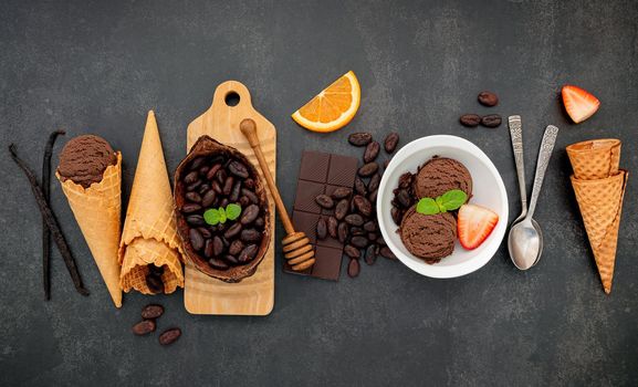 Chocolate ice cream flavours in bowl with dark chocolate and cacao nibs setup on dark stone background .