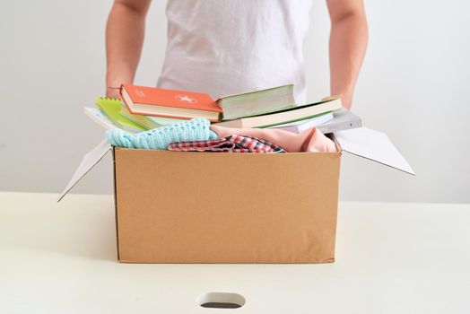 Man holding a book and clothes donate box. Donation concept.