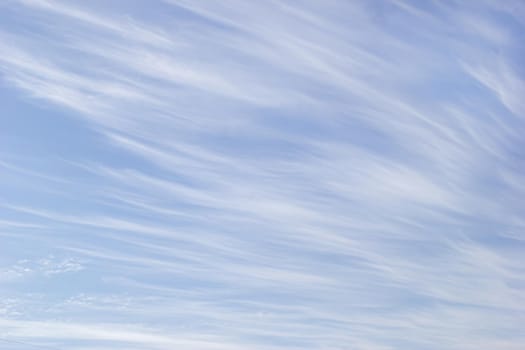 White cirrus clouds on the background blue sky.