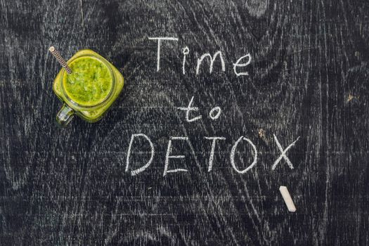 TIME TO DETOX chalk inscription on the wooden table and Green smoothies made of spinach. Healthy eating and sports concept.