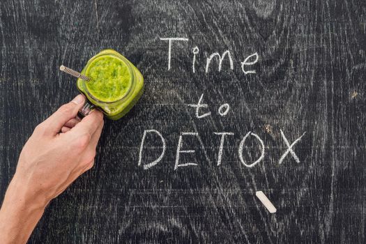 TIME TO DETOX chalk inscription on the wooden table and Green smoothies made of spinach. Healthy eating and sports concept.