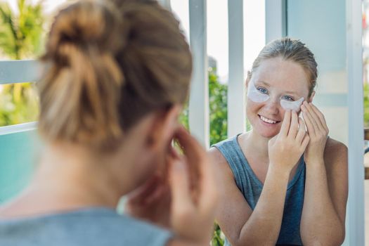 Portrait of Beauty Red-haired woman with eye patches showing an effect of perfect skin. Spa Girl.