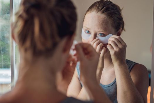 Portrait of Beauty Red-haired woman with eye patches showing an effect of perfect skin. Spa Girl.