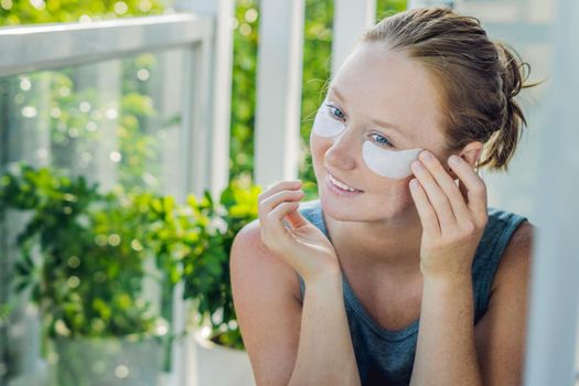 Portrait of Beauty Red-haired woman with eye patches showing an effect of perfect skin. Spa Girl.