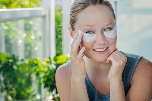 Portrait of Beauty Red-haired woman with eye patches showing an effect of perfect skin. Spa Girl.