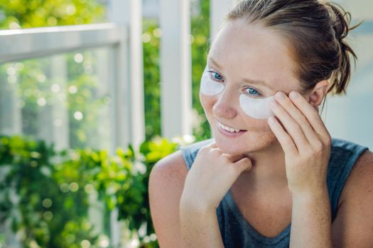 Portrait of Beauty Red-haired woman with eye patches showing an effect of perfect skin. Spa Girl.