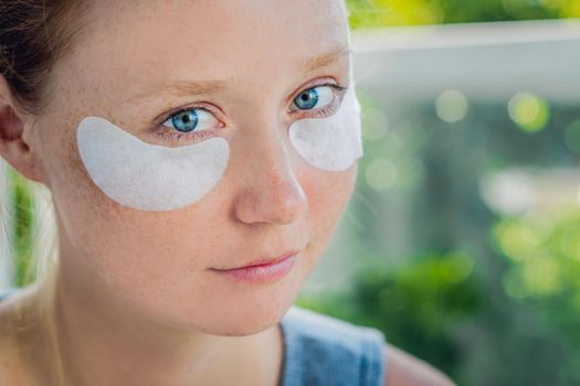 Portrait of Beauty Red-haired woman with eye patches showing an effect of perfect skin. Spa Girl.