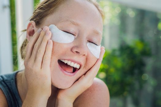 Portrait of Beauty Red-haired woman with eye patches showing an effect of perfect skin. Spa Girl.