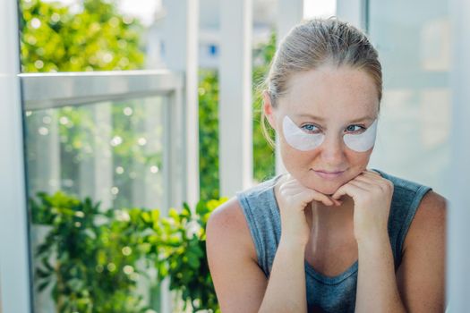 Portrait of Beauty Red-haired woman with eye patches showing an effect of perfect skin. Spa Girl.