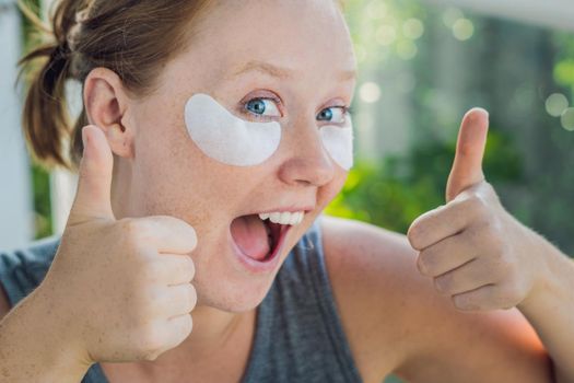 Portrait of Beauty Red-haired woman with eye patches showing an effect of perfect skin. Spa Girl.