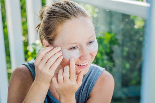 Portrait of Beauty Red-haired woman with eye patches showing an effect of perfect skin. Spa Girl.