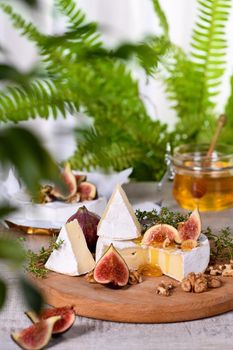 Brie cheese served on a wooden board with figs, walnuts and honey