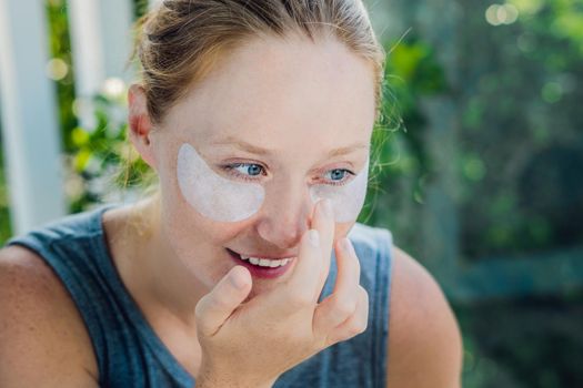 Portrait of Beauty Red-haired woman with eye patches showing an effect of perfect skin. Spa Girl.