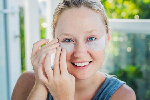 Portrait of Beauty Red-haired woman with eye patches showing an effect of perfect skin. Spa Girl.