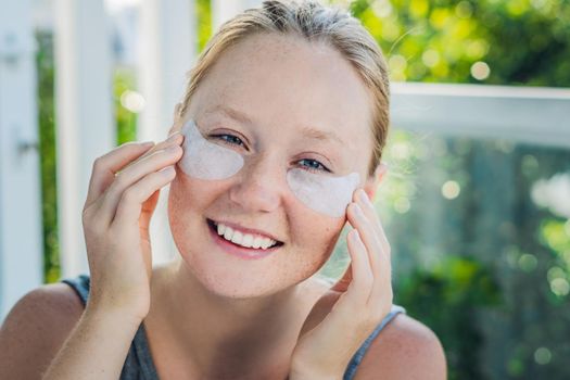 Portrait of Beauty Red-haired woman with eye patches showing an effect of perfect skin. Spa Girl.